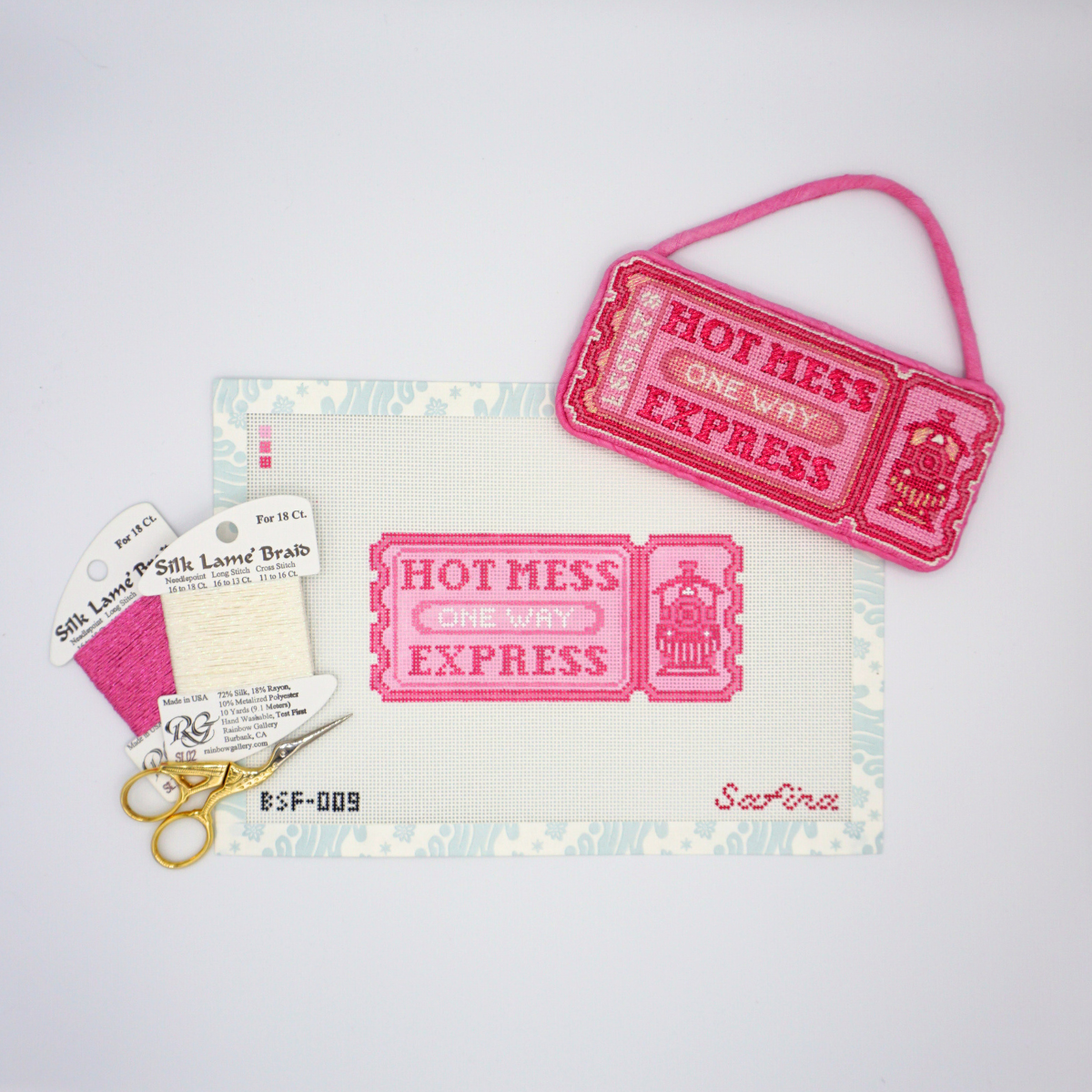 Pink hot mess express one way train ticket needlepoint canvas with fiber threads, scissors, and finished ornament