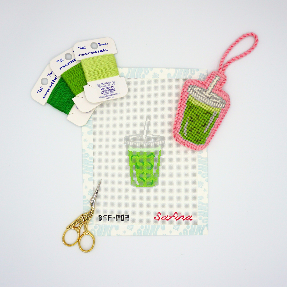 Iced matcha latte in to go cup needlepoint canvas design with essentials thread, scissors, and finished iced matcha latte needlepoint canvas