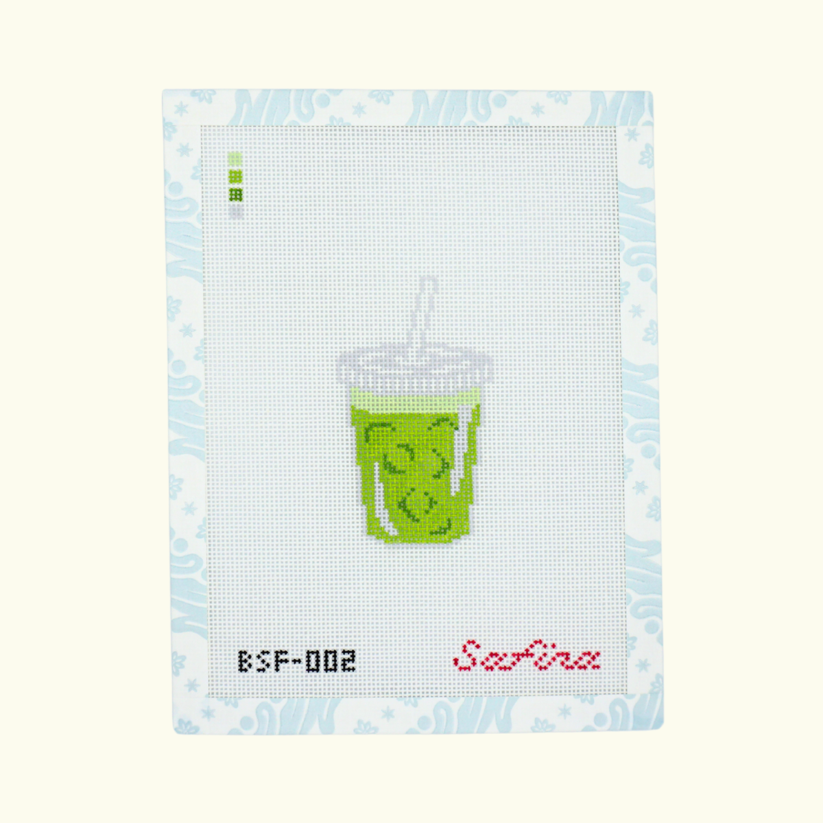 Iced matcha latte in a to go cup with straw needlepoint canvas design